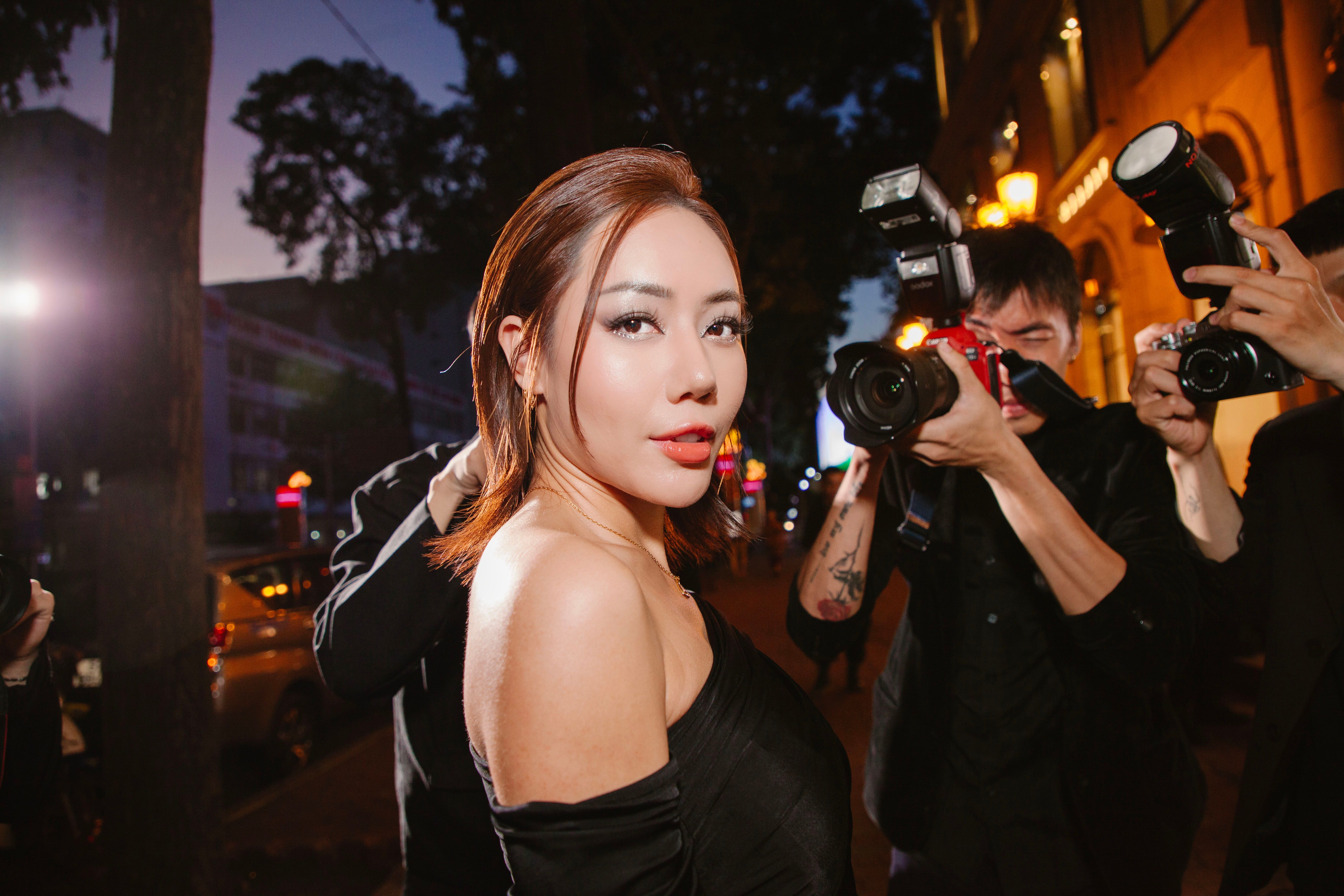 Glamorous public figure posing confidently for photographers at a night event