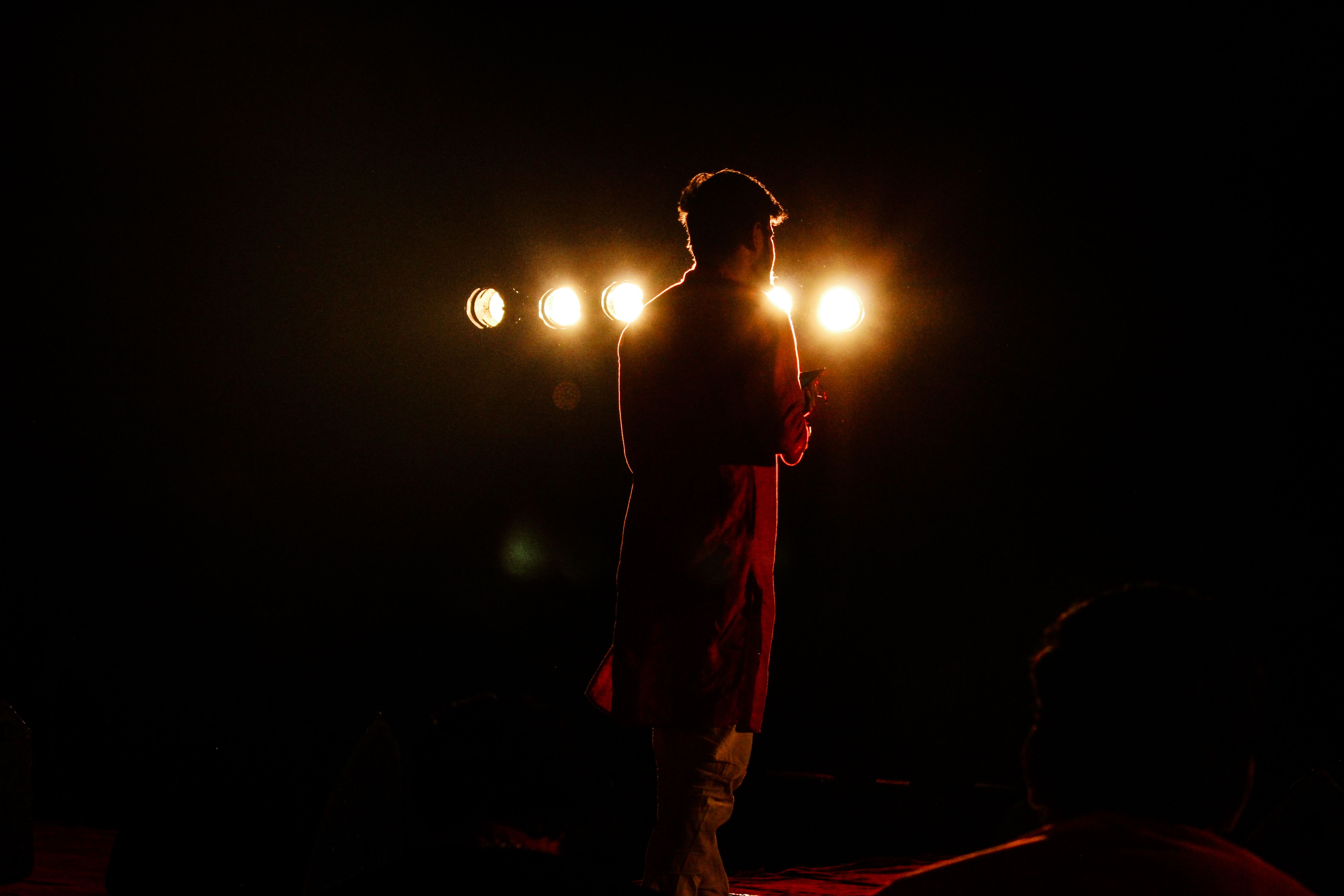 Silhouette of a performer under a stage spotlight, evoking the rise and fall of fame