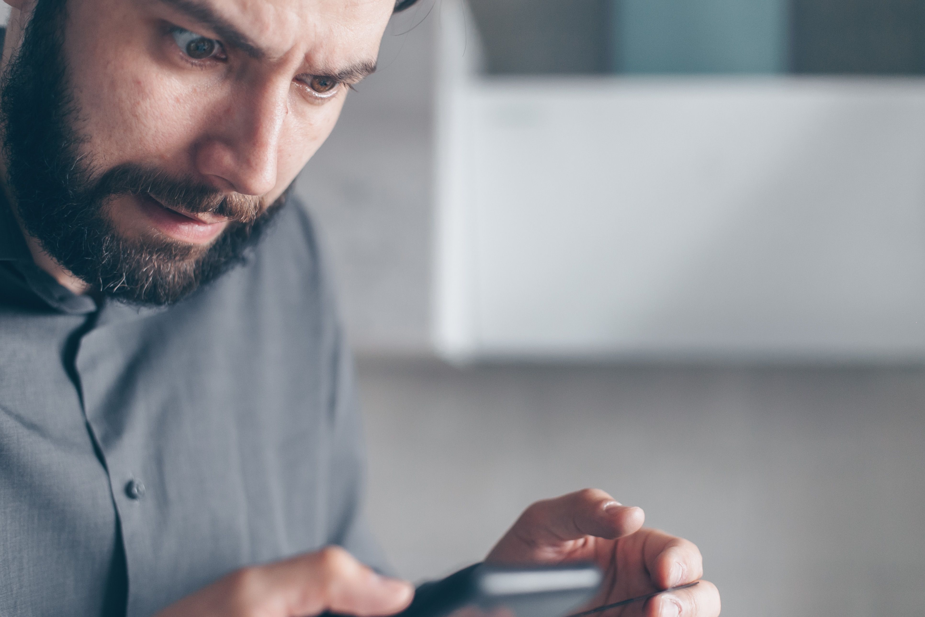 Shocked man looking at his smartphone after receiving a data breach notification