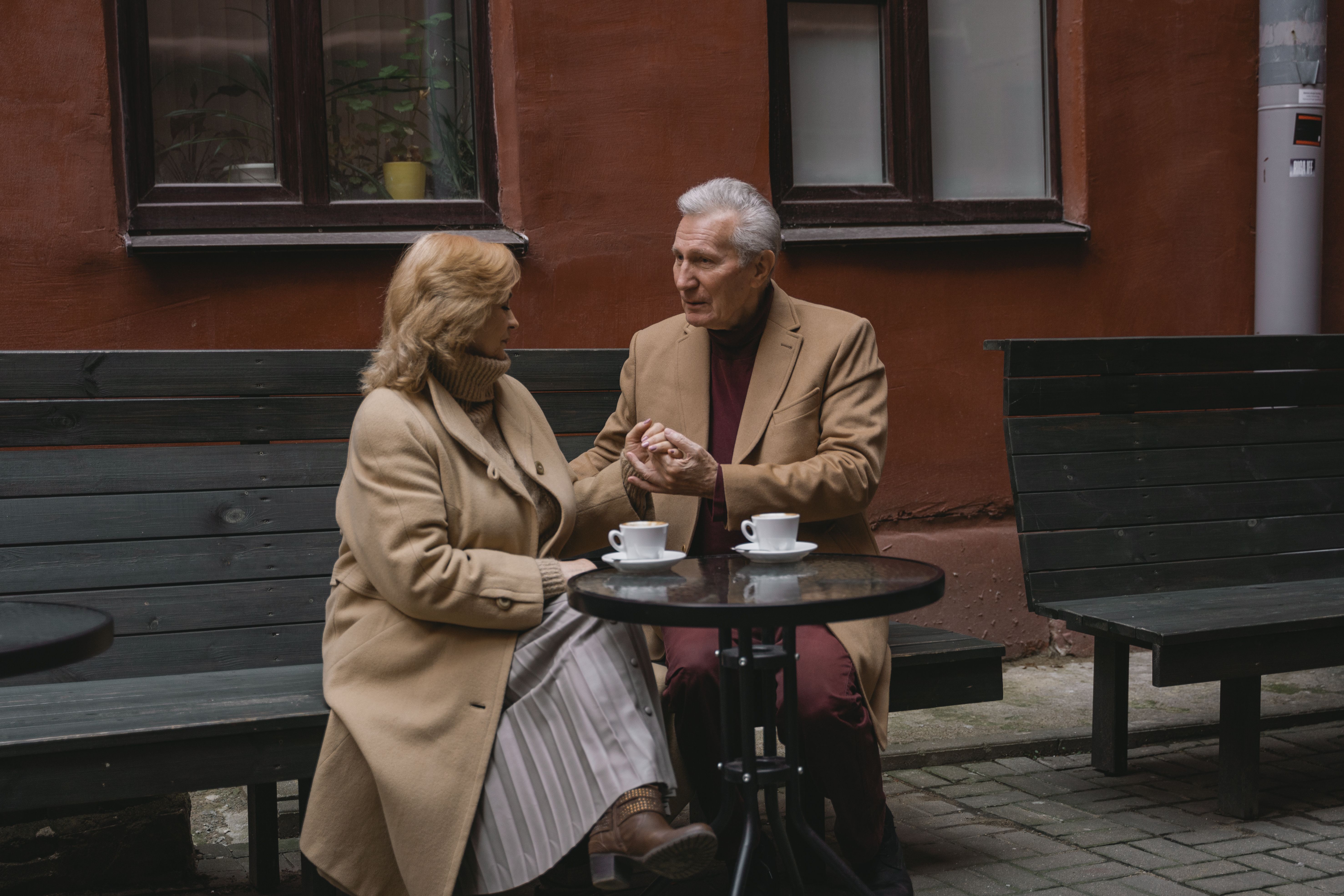 An older couple talking over coffee at an outdoor cafe, suggesting the thoughtful conversations relationships require.