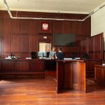 Spacious courtroom with wooden panels and seating, illustrating the scale of major legal proceedings.