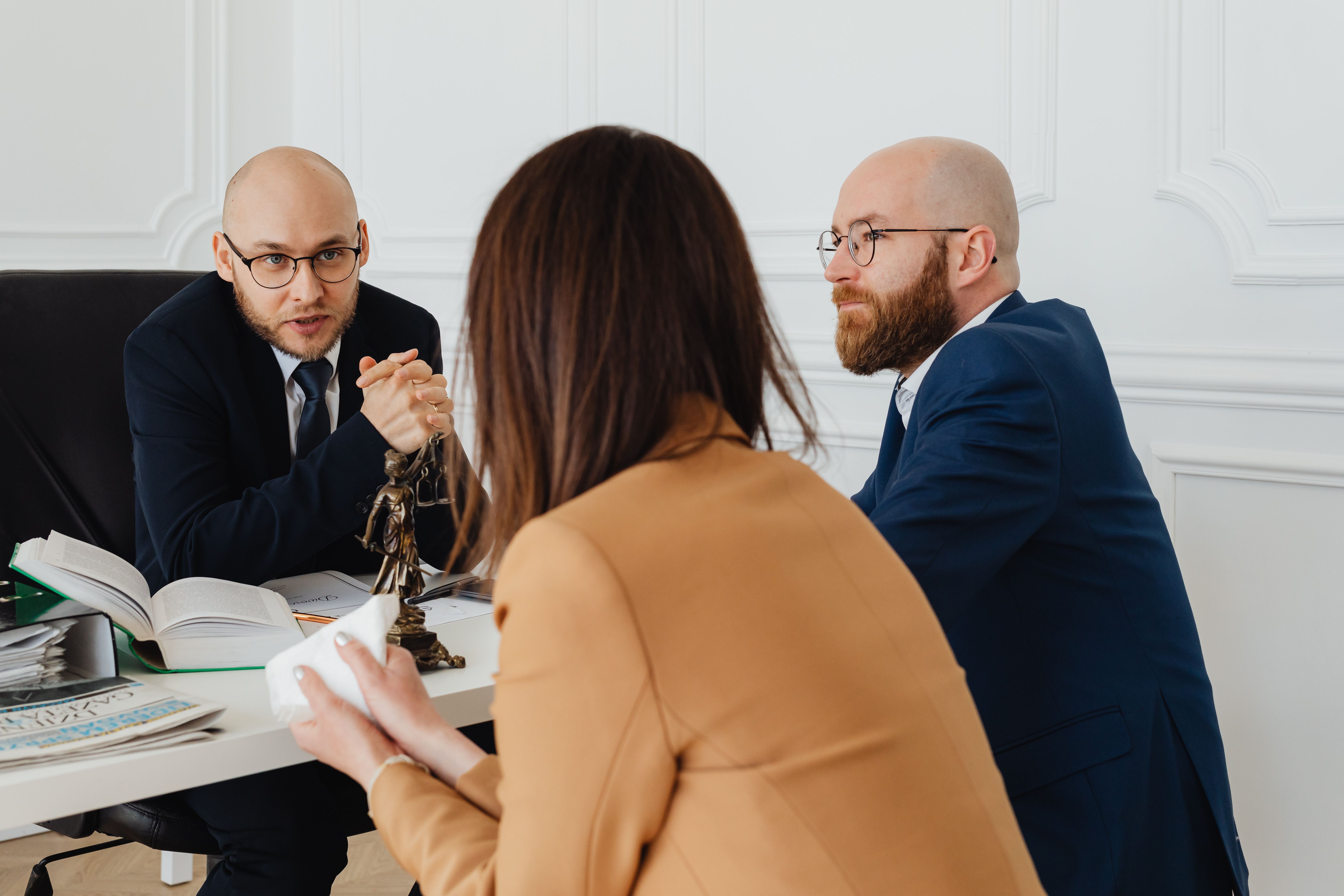 Lawyers discussing legal matters in a modern office, illustrating the personnel and strategy costs of a major case.