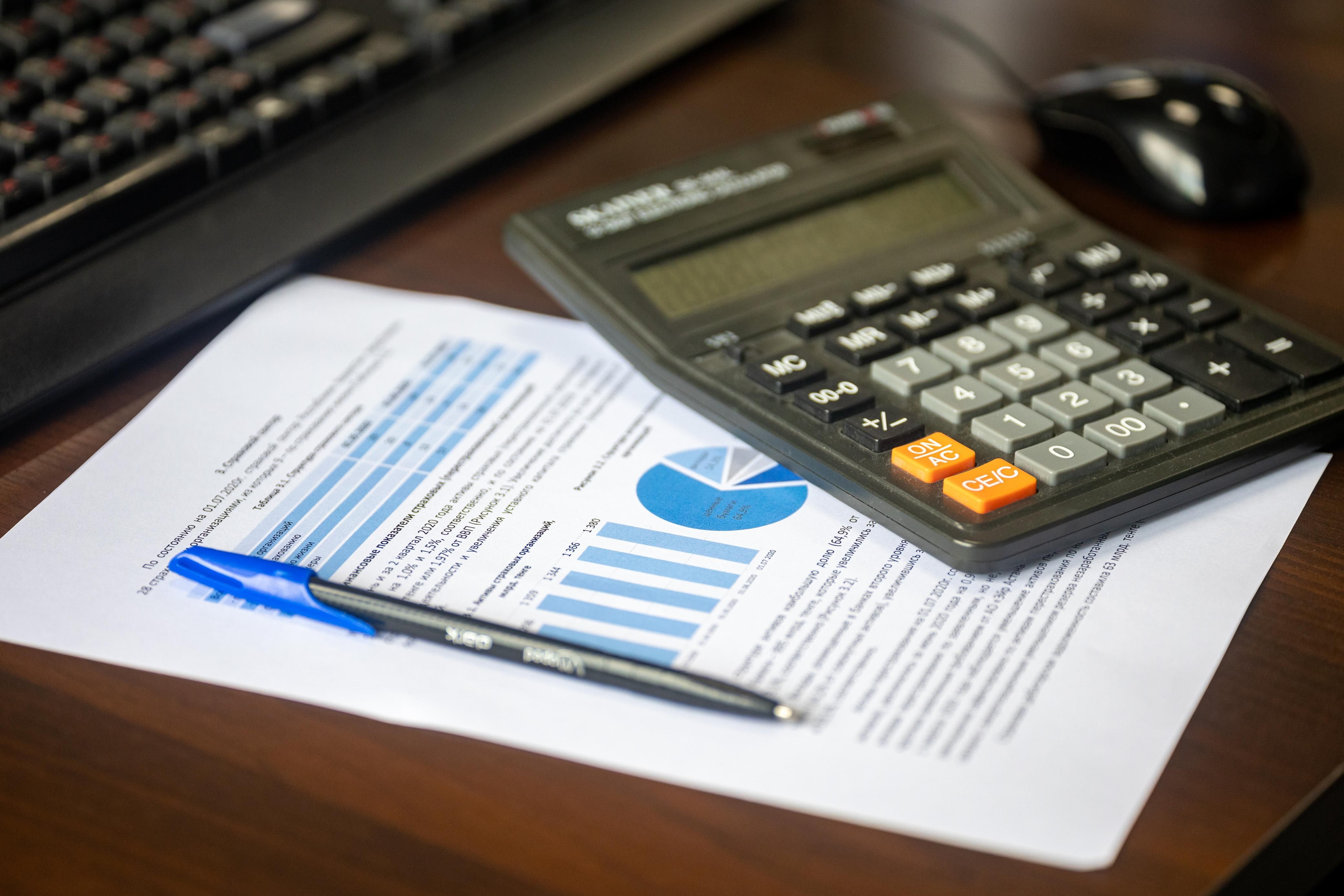 Calculator beside a financial report and pen, representing budgeting and cost analysis for litigation.