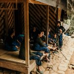 A family gathering outside a wooden house in rural Banten, Indonesia, showing traditional community life